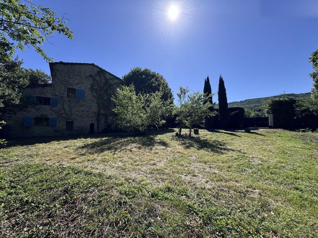 Maison en pierre entourée de verdure et de cyprès, à La Touche dans la Drôme